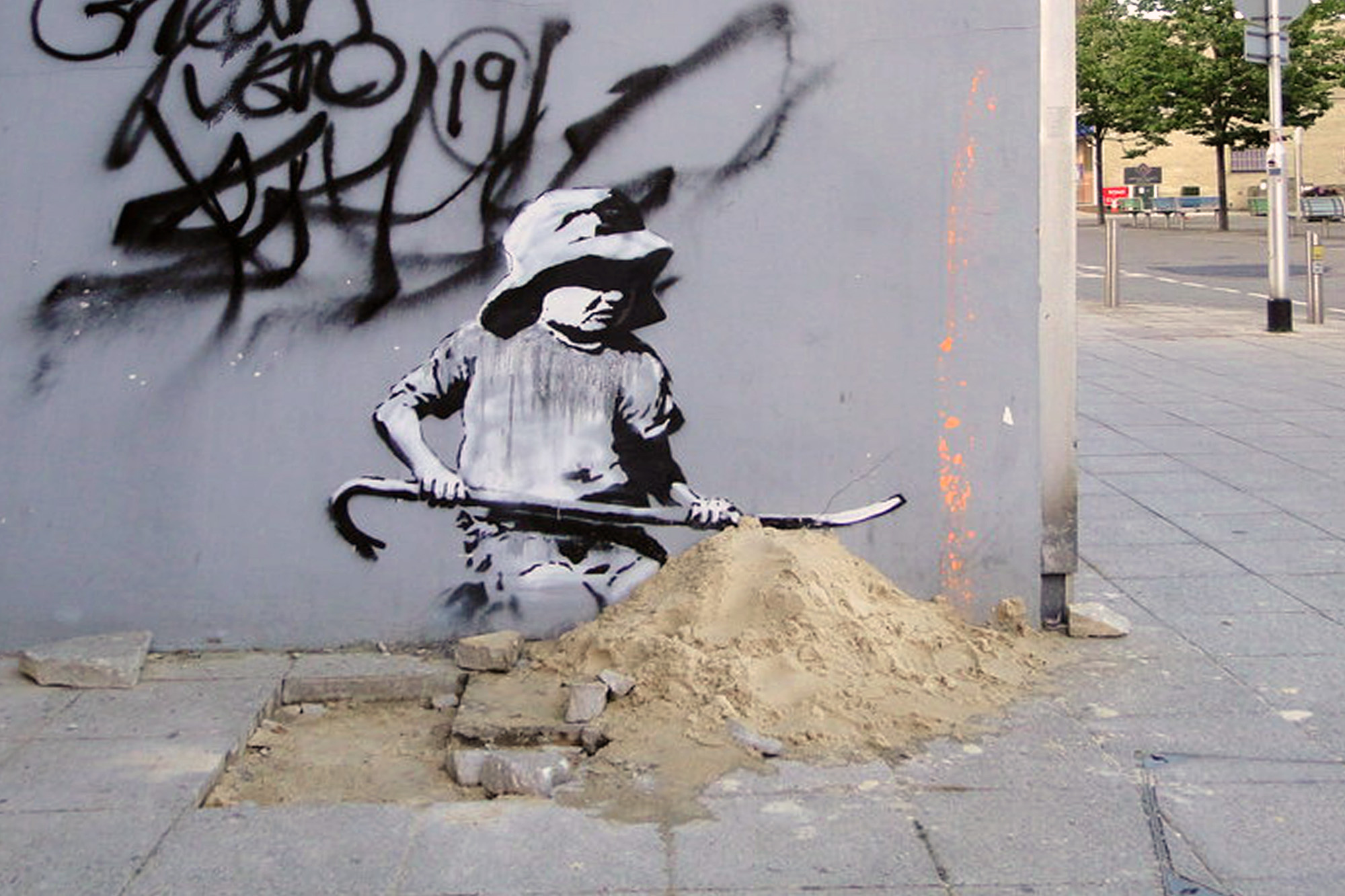 stensil of a child digging in the sand, the subject of a graffiti artwork bearing the hallmarks of street artist Banksy on a wall in Lowestoft on the East coast of England on August 8, 2021